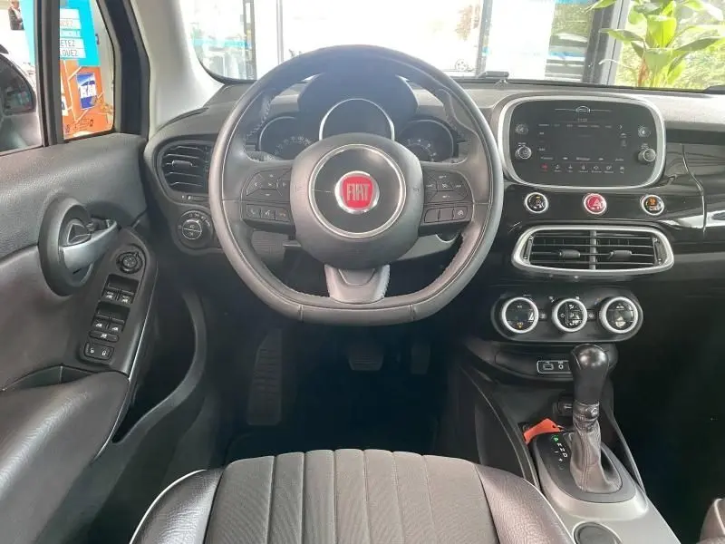 Intérieur de la Fiat 500X 2018 vue du poste de conduite, volant cuir multifonction et écran tactile central noir.
