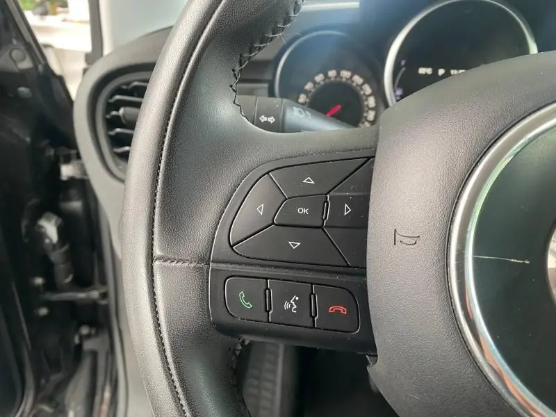 Gros plan sur le volant cuir noir de la Fiat 500X 2018 avec commandes audio et téléphoniques intégrées.