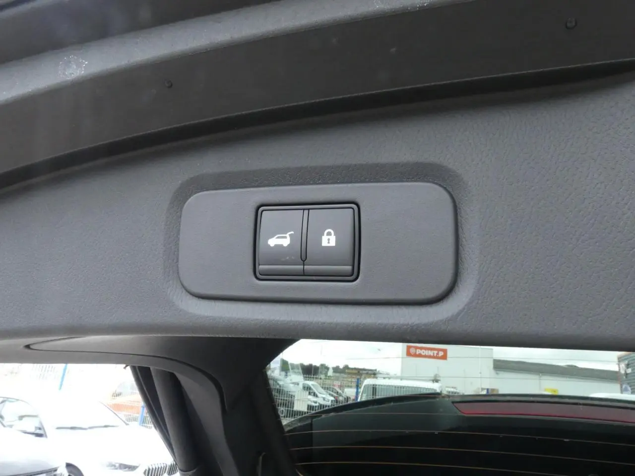 Boutons de hayon électrique et verrouillage intégrés sur le coffre d'un Nissan Qashqai gris métallisé, vue intérieure arrière.