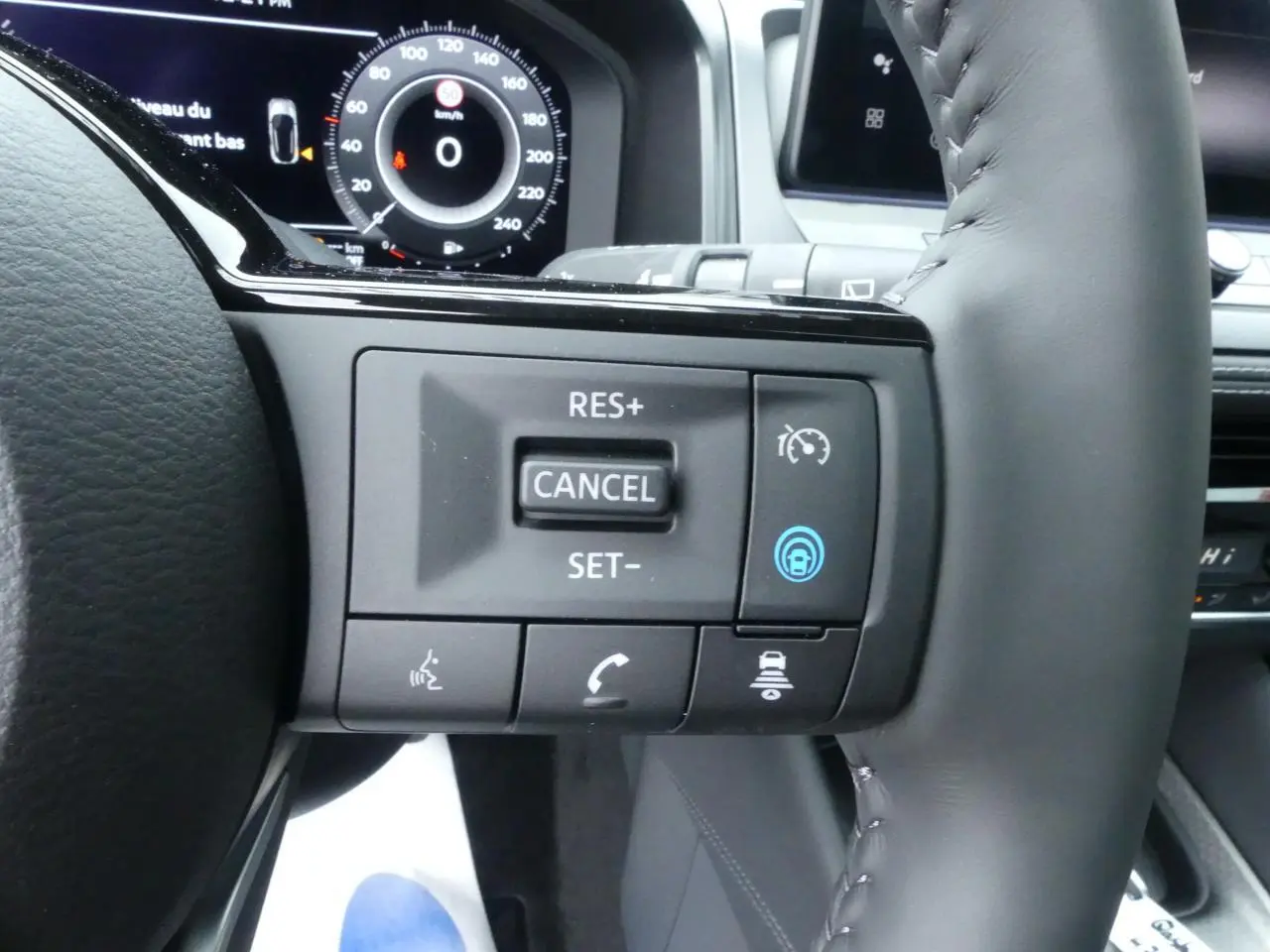 Gros plan sur les commandes au volant à droite du Nissan Qashqai 2025, avec affichage numérique du tableau de bord en arrière-plan.