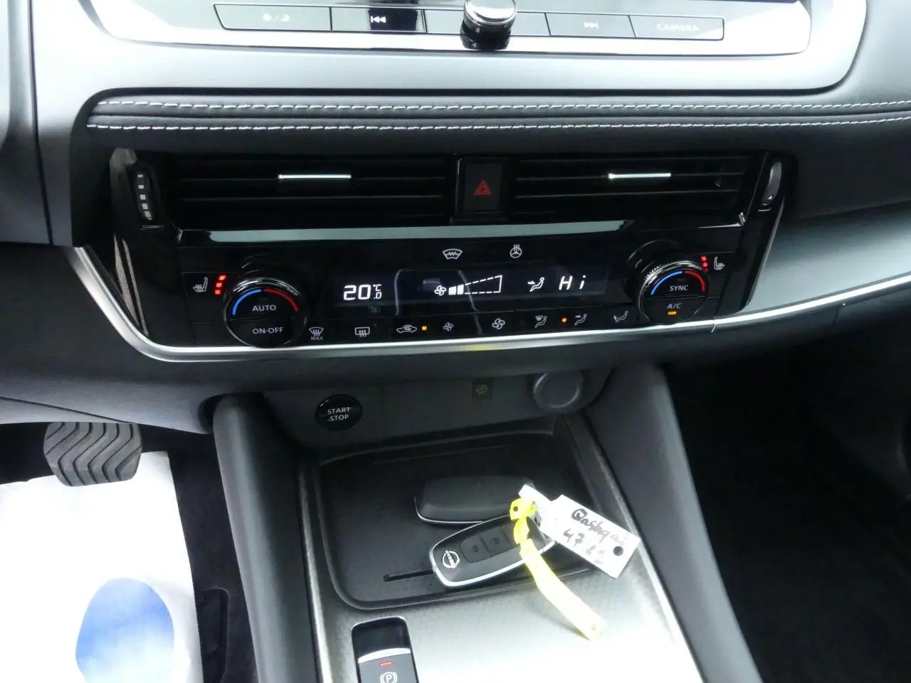 Détail de la console centrale du Nissan Qashqai 1.5 e-Power 2025 avec commandes climatisation et clé intelligente posée.