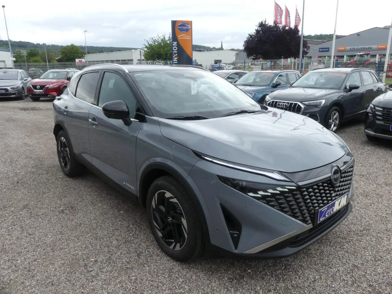 Nissan Qashqai 1.5 e-Power gris métallisé en 3/4 avant droit avec calandre distinctive et jantes noires.