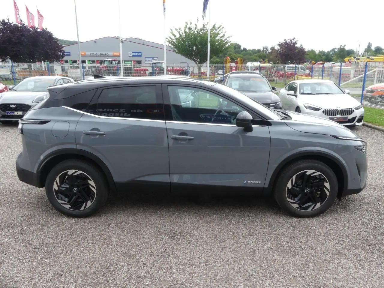 Profil côté gauche du Nissan Qashqai 1.5 e-Power gris métallisé avec jantes alliage noires et toit panoramique noir.