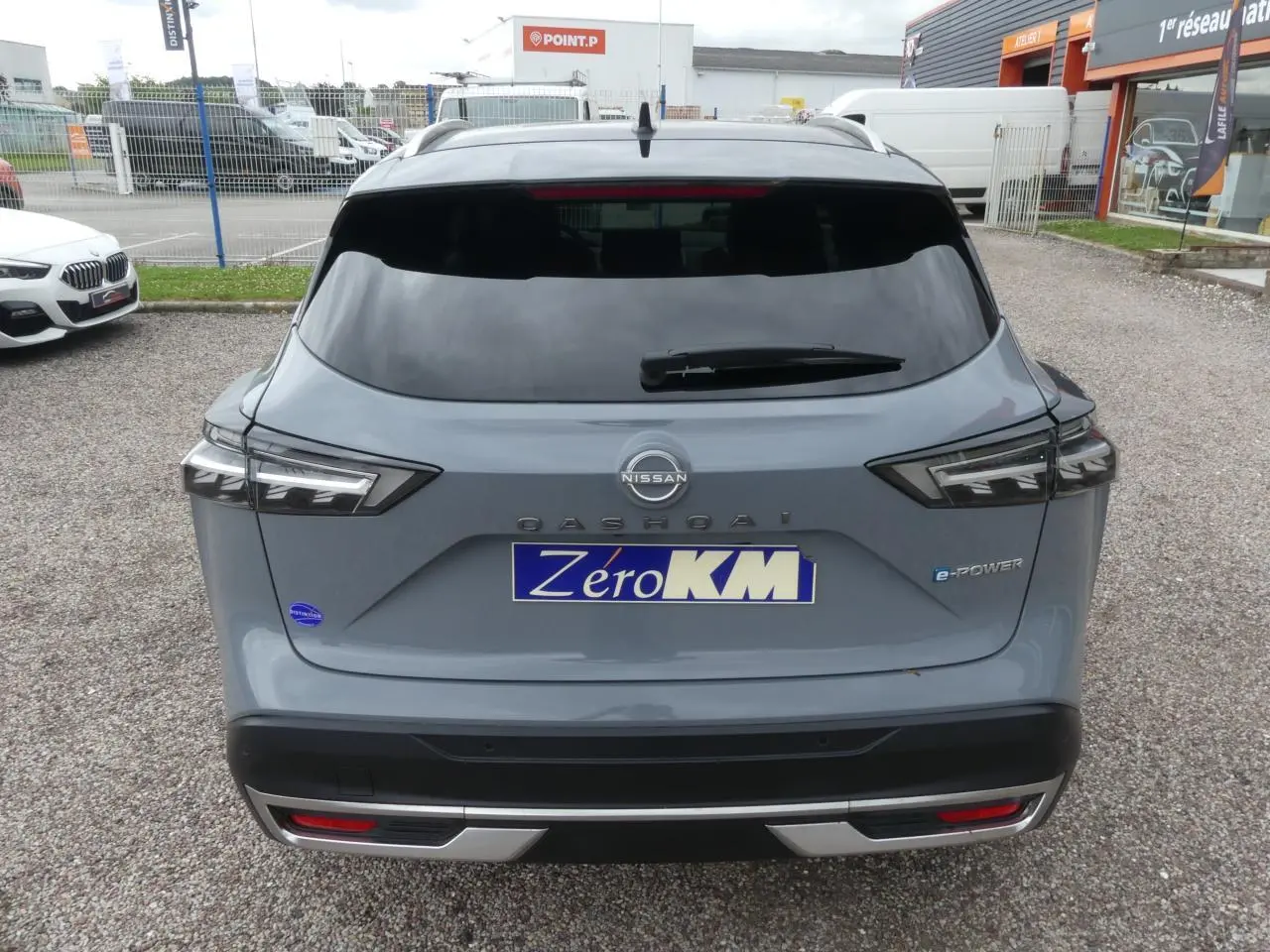 Vue arrière du Nissan Qashqai gris métallisé avec badges e-Power et hayon fermé sur parking.