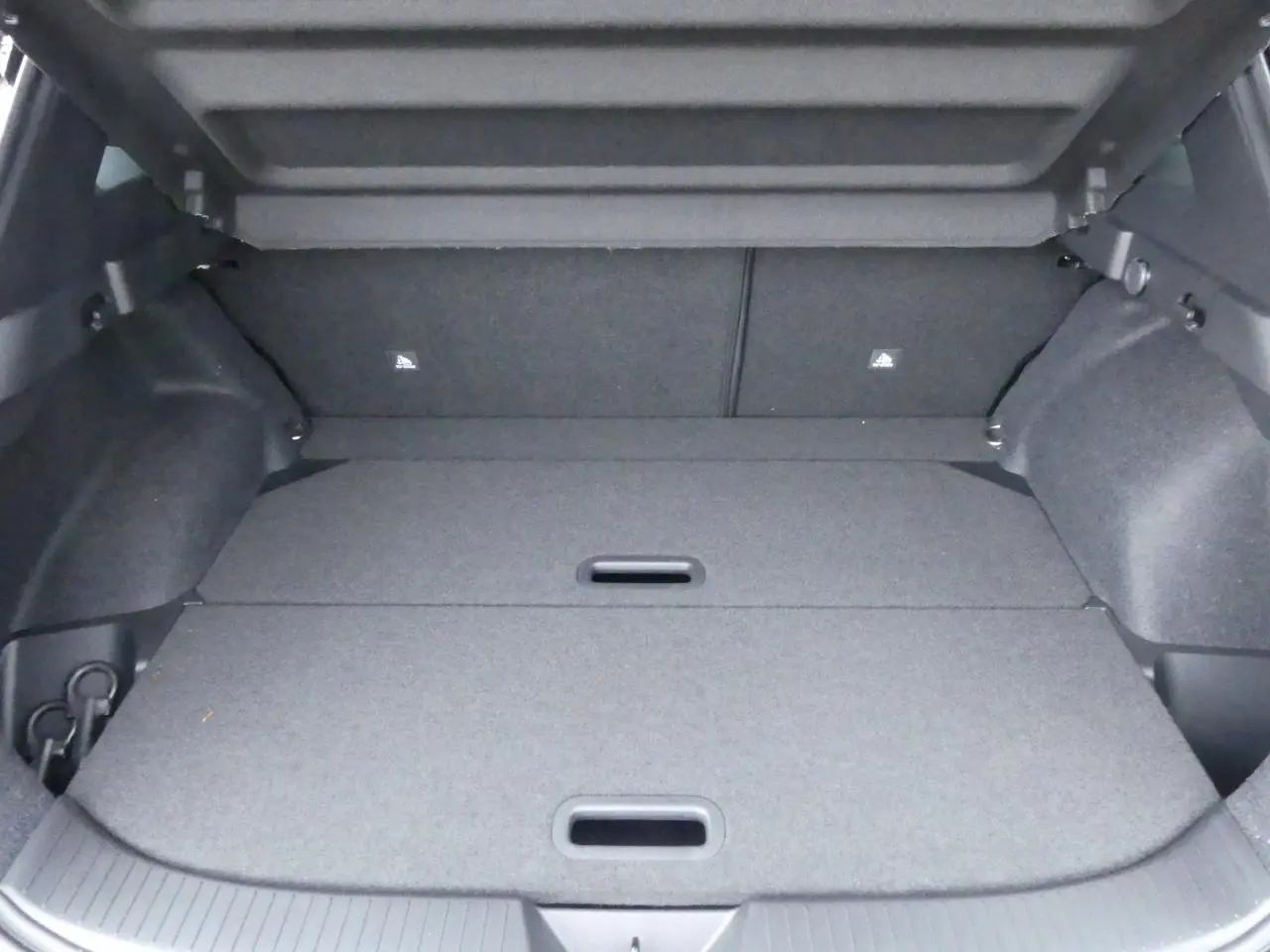 Coffre spacieux du Nissan Qashqai 1.5 e-Power gris métallisé avec plancher modulable et crochets de fixation visibles.