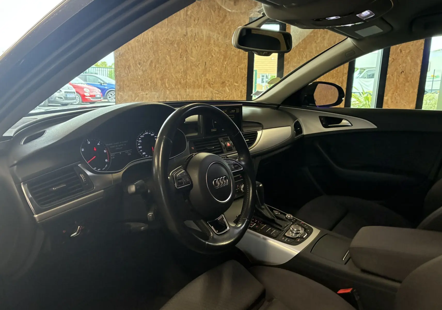 Intérieur noir de l'Audi A6 Avant 2017, vue côté conducteur montrant tableau de bord et volant multifonction.