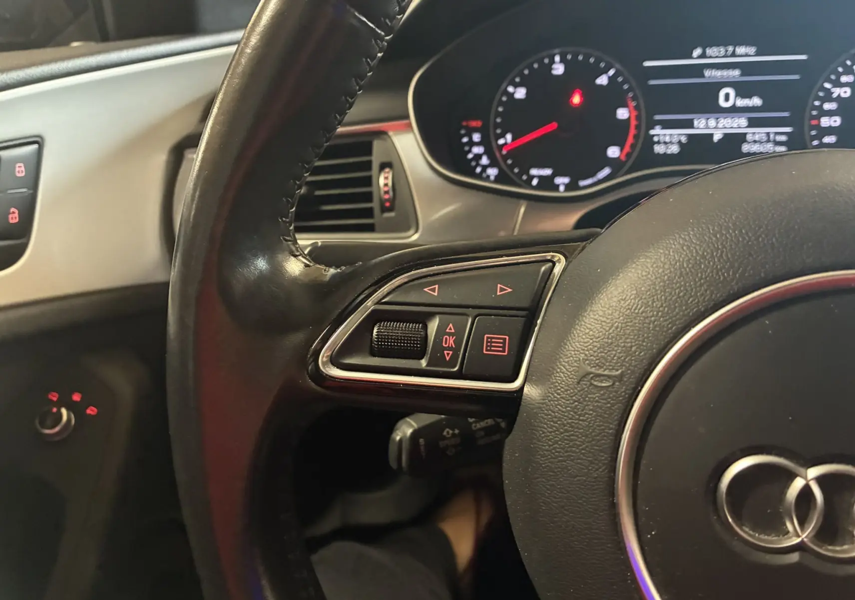 Gros plan sur le volant noir de l'Audi A6 Avant 2017 avec commandes intégrées et tableau de bord numérique allumé.