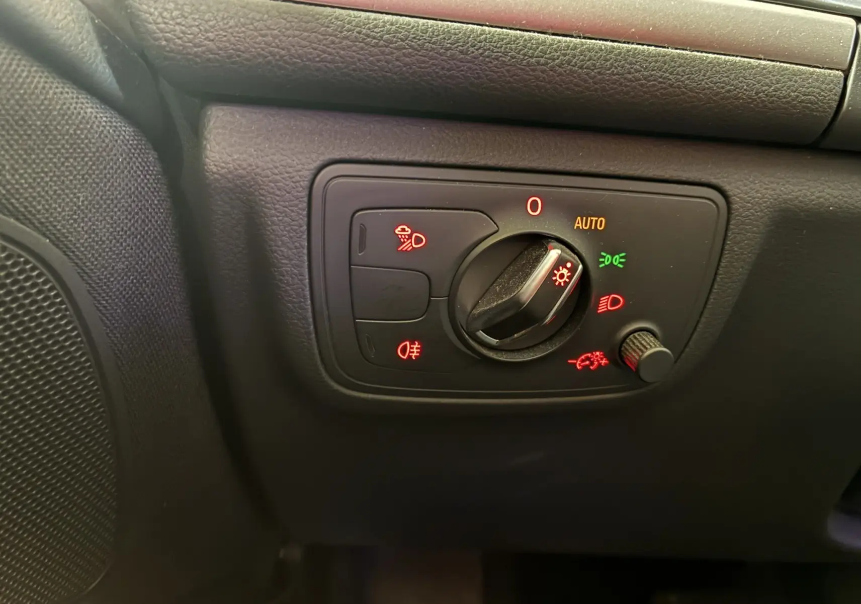 Gros plan sur le panneau de commande des phares noir à gauche du tableau de bord de l'Audi A6 Avant 2017.