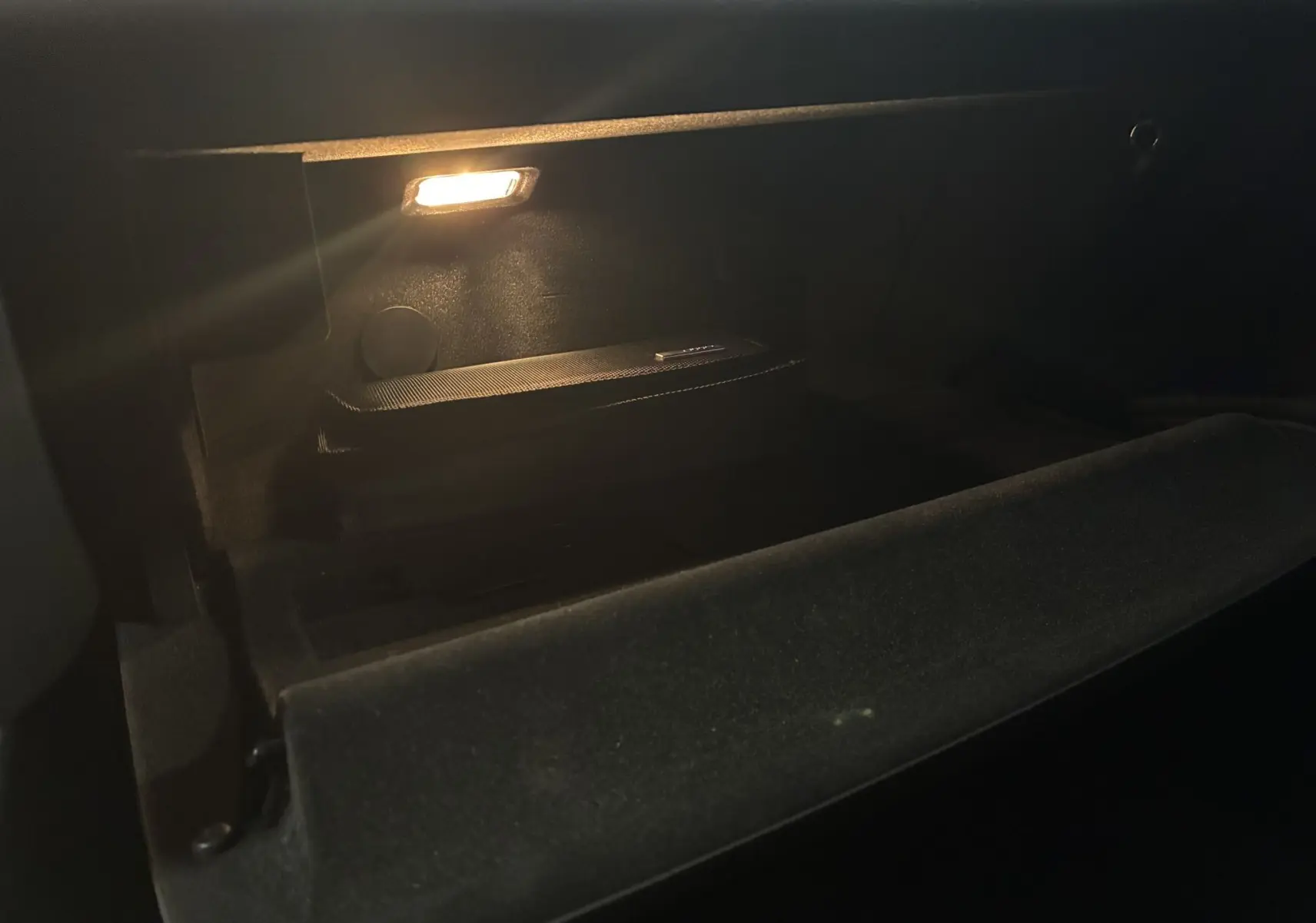 Intérieur de la boîte à gants éclairée de l'Audi A6 Avant noire 2017, version 2.0 TDI Ambition Luxe.