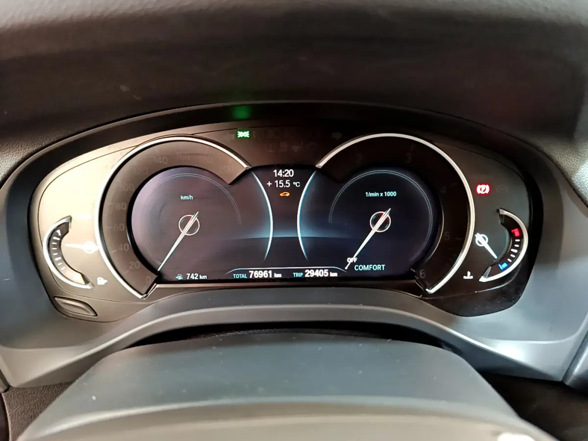 Vue rapprochée du tableau de bord numérique de la BMW X3 noire, affichant vitesse, compte-tours et température extérieure.