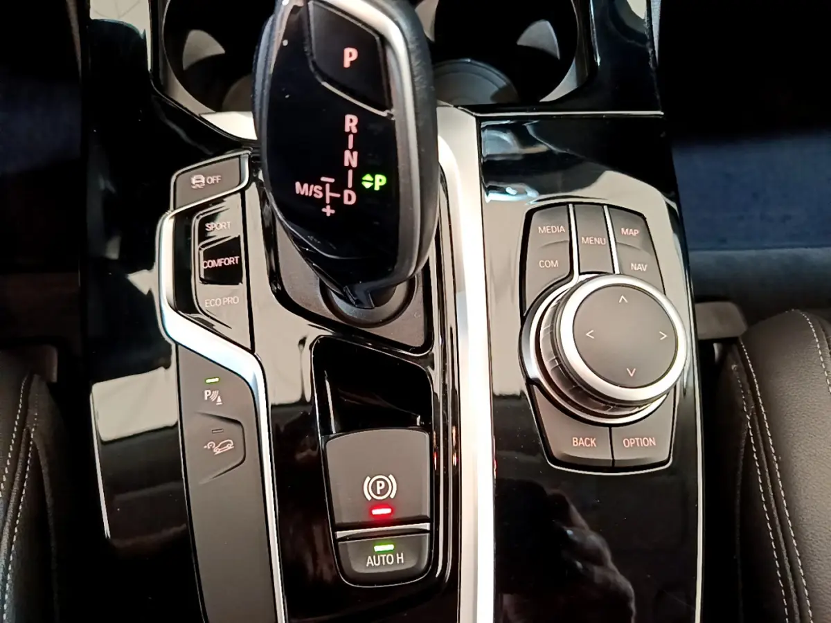 Vue rapprochée de la console centrale noire brillante du BMW X3 xDrive20d 2020 avec levier de vitesses et commandes multimédia.