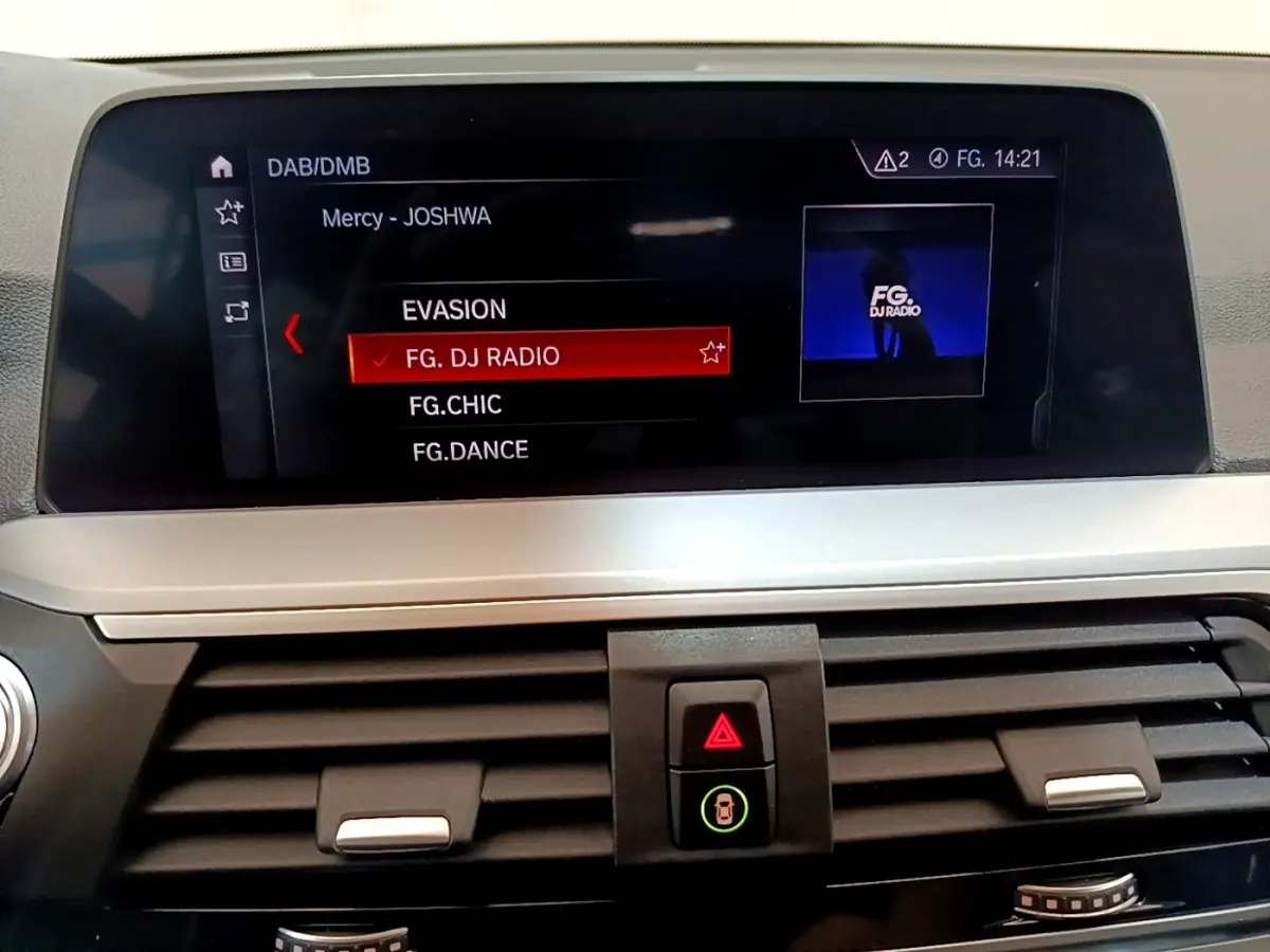 Écran central du tableau de bord du BMW X3 noir 2020 affichant la sélection radio FG. DJ RADIO en intérieur moderne