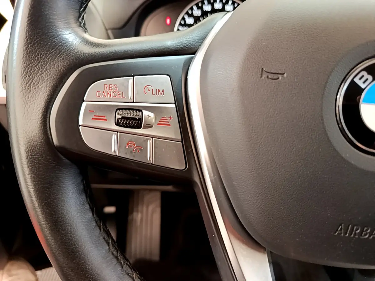 Gros plan sur la partie gauche du volant cuir noir du BMW X3 xDrive20d 2020 avec commandes de régulateur de vitesse.