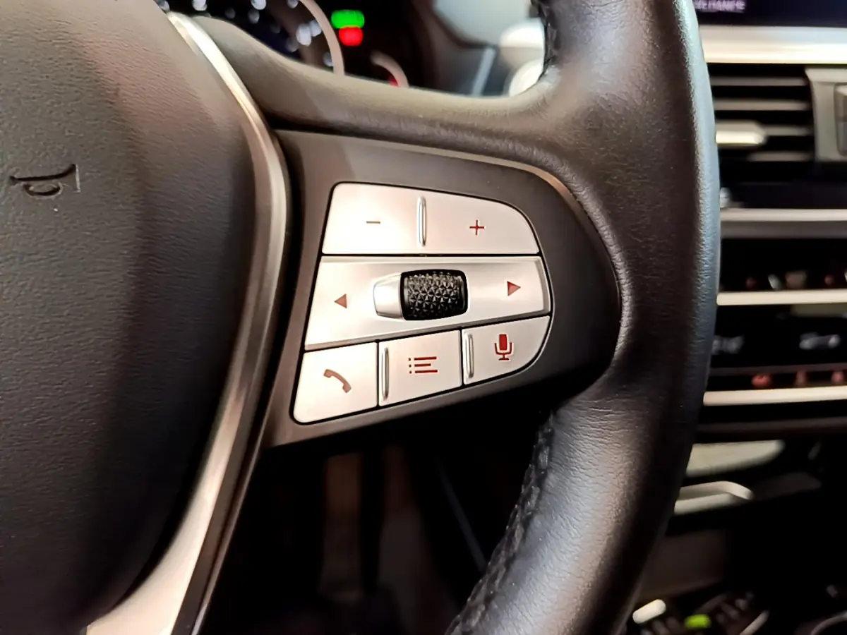 Gros plan sur les commandes multifonctions côté gauche du volant cuir noir du BMW X3 xDrive20d 2020.