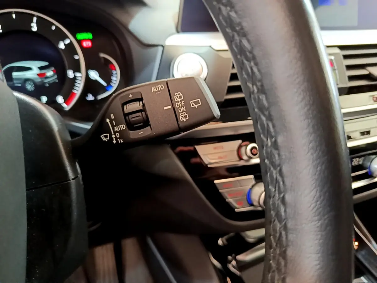 Gros plan sur la manette d’essuie-glace à gauche du volant cuir noir du BMW X3 xDrive20d 2020, tableau de bord en arrière-plan.