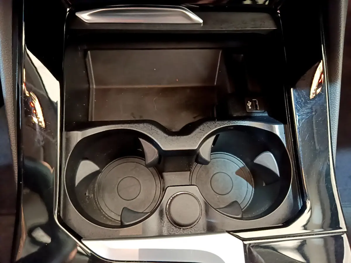 Gros plan sur les porte-gobelets noirs et prise USB dans la console centrale du BMW X3 xDrive20d Lounge 2020.