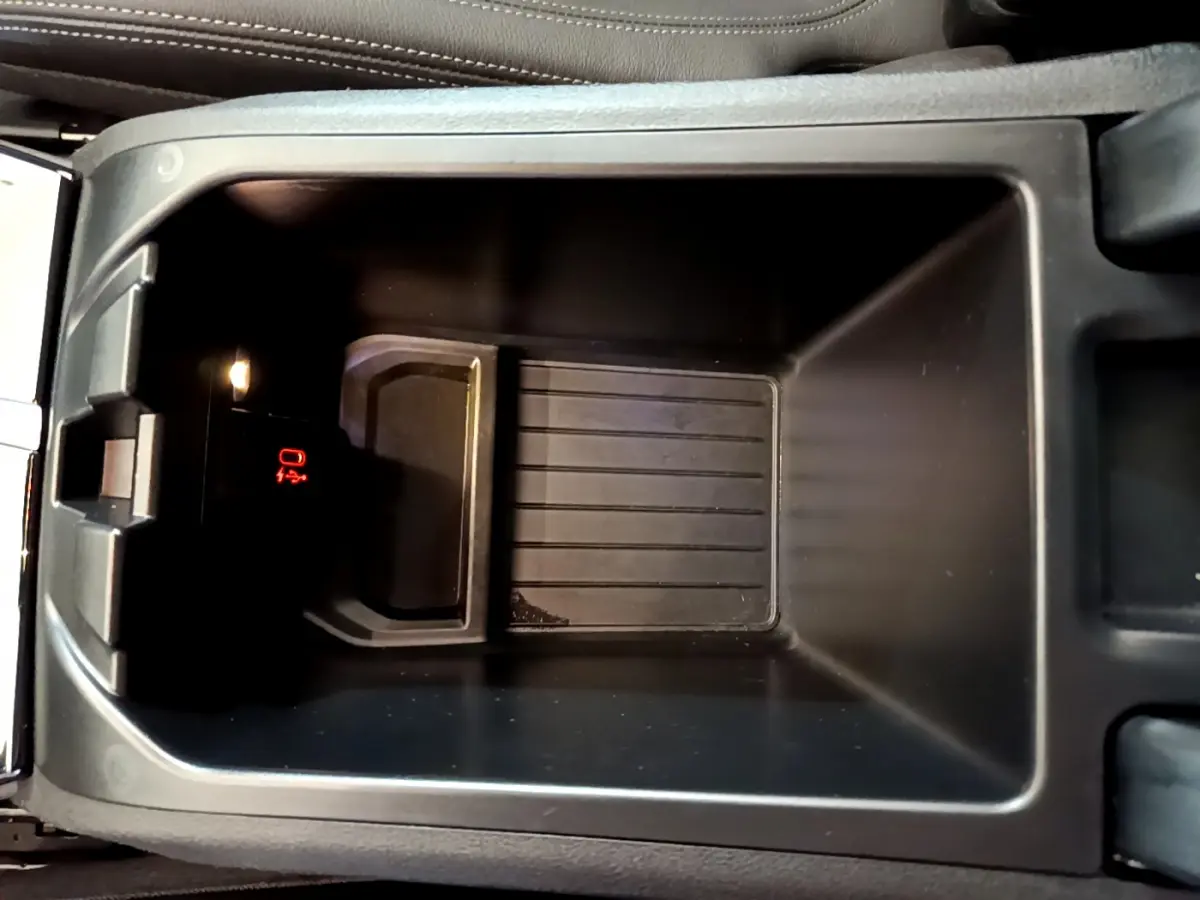 Vue rapprochée du rangement central intérieur du BMW X3 noir, avec éclairage et indicateur rouge visible.