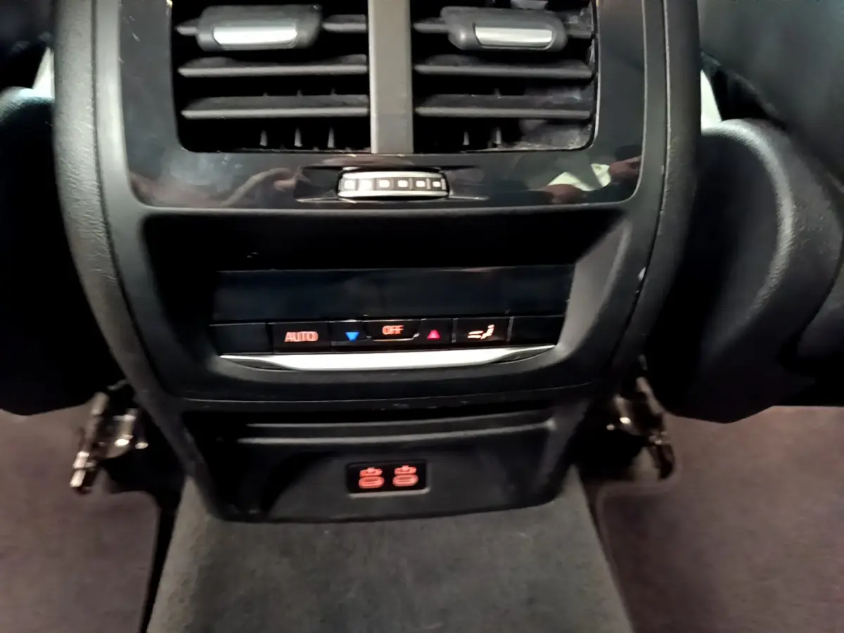 Vue rapprochée de la console arrière noire du BMW X3 xDrive20d 2020 avec commandes climatisation et prises 12V.