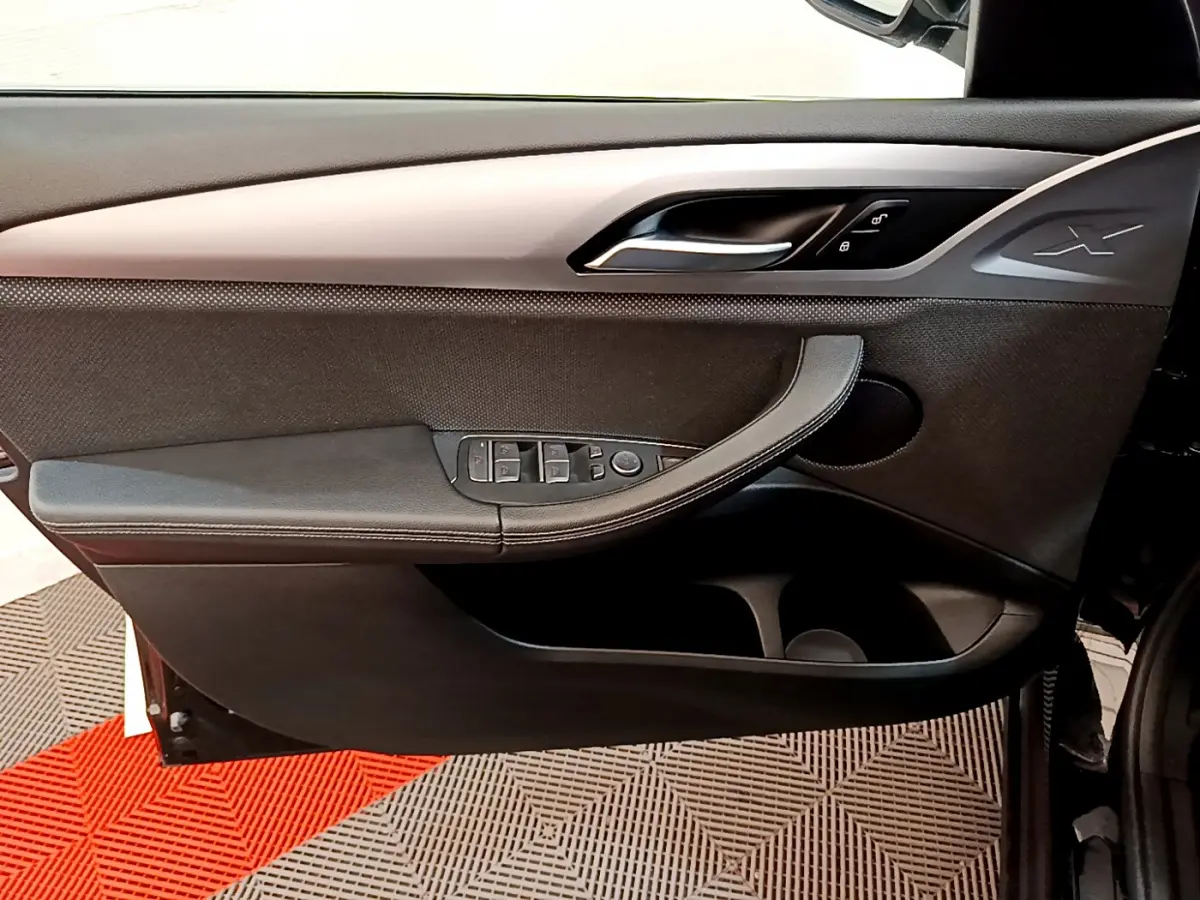 Porte intérieure côté gauche noire du BMW X3 xDrive20d 2020 avec poignée intégrée et commandes électriques des vitres.