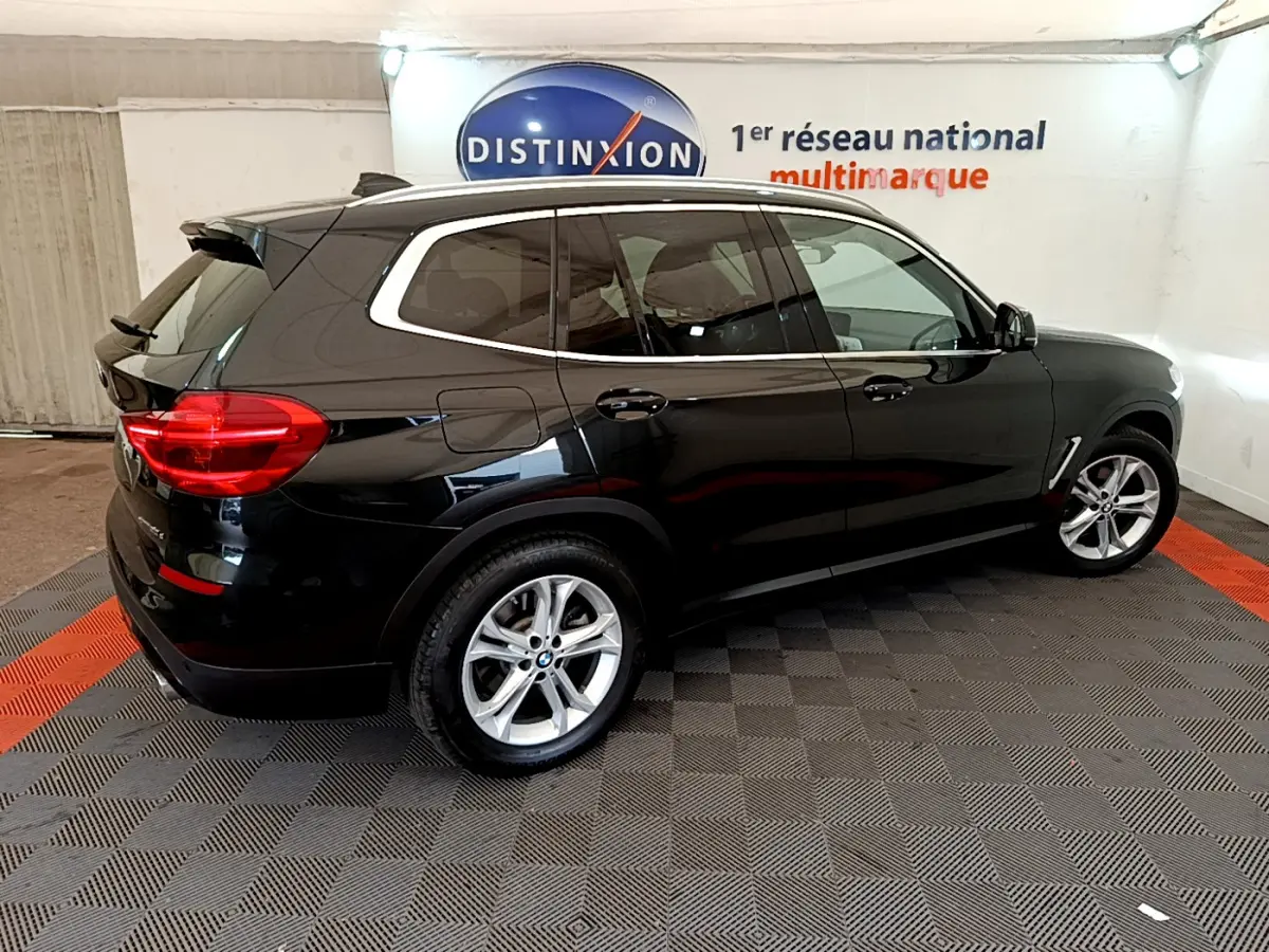 BMW X3 xDrive20d noir vue de profil côté droit dans un showroom avec sol damier gris et rouge