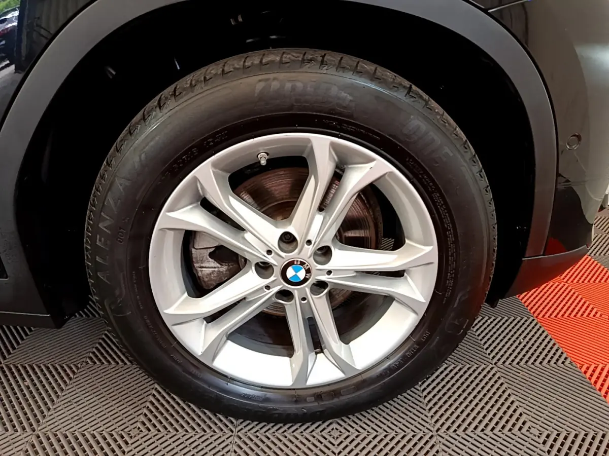Gros plan sur la roue avant droite du BMW X3 noir 2020, mettant en valeur la jante alliage argentée et le logo BMW central.