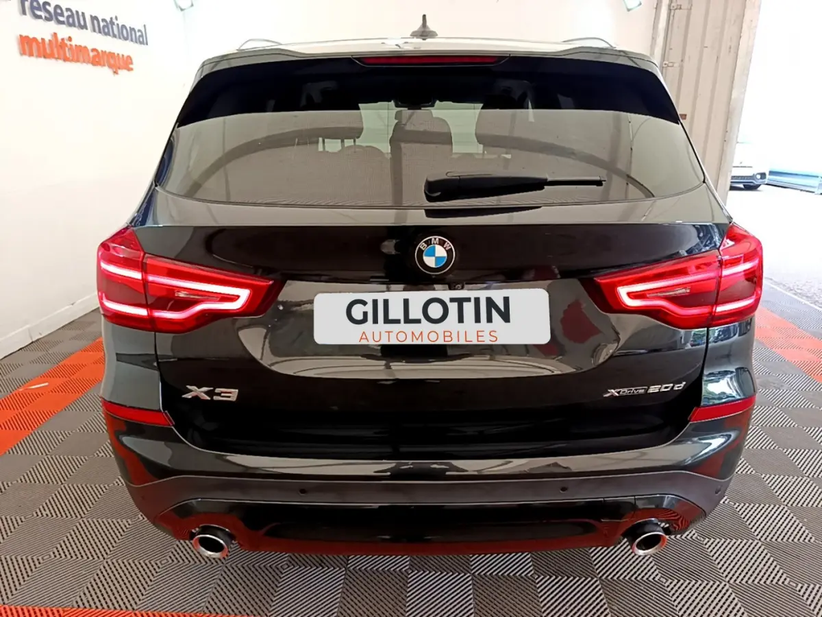Vue arrière d'un BMW X3 noir xDrive20d avec feux LED allumés et double sortie d'échappement visible.