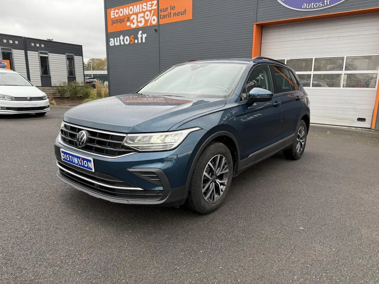 Volkswagen Tiguan bleu nuit métallisé vu en 3/4 avant droit avec jantes alliage et feux LED allumés.