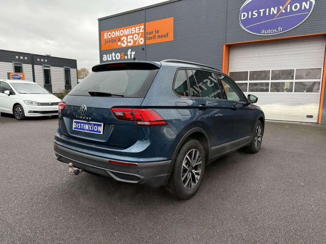 Volkswagen Tiguan bleu nuit métallisé vu en 3/4 arrière droit avec crochet d'attelage et jantes alliage 17 pouces.