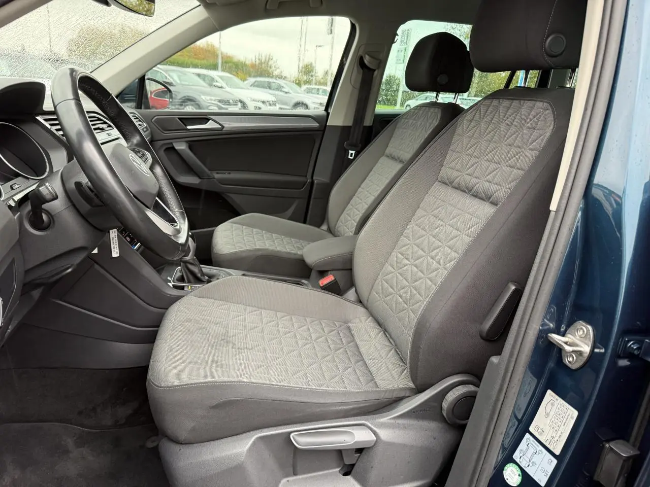 Vue intérieure côté conducteur du Volkswagen Tiguan 2022 bleu nuit, sièges tissu gris à motifs géométriques.