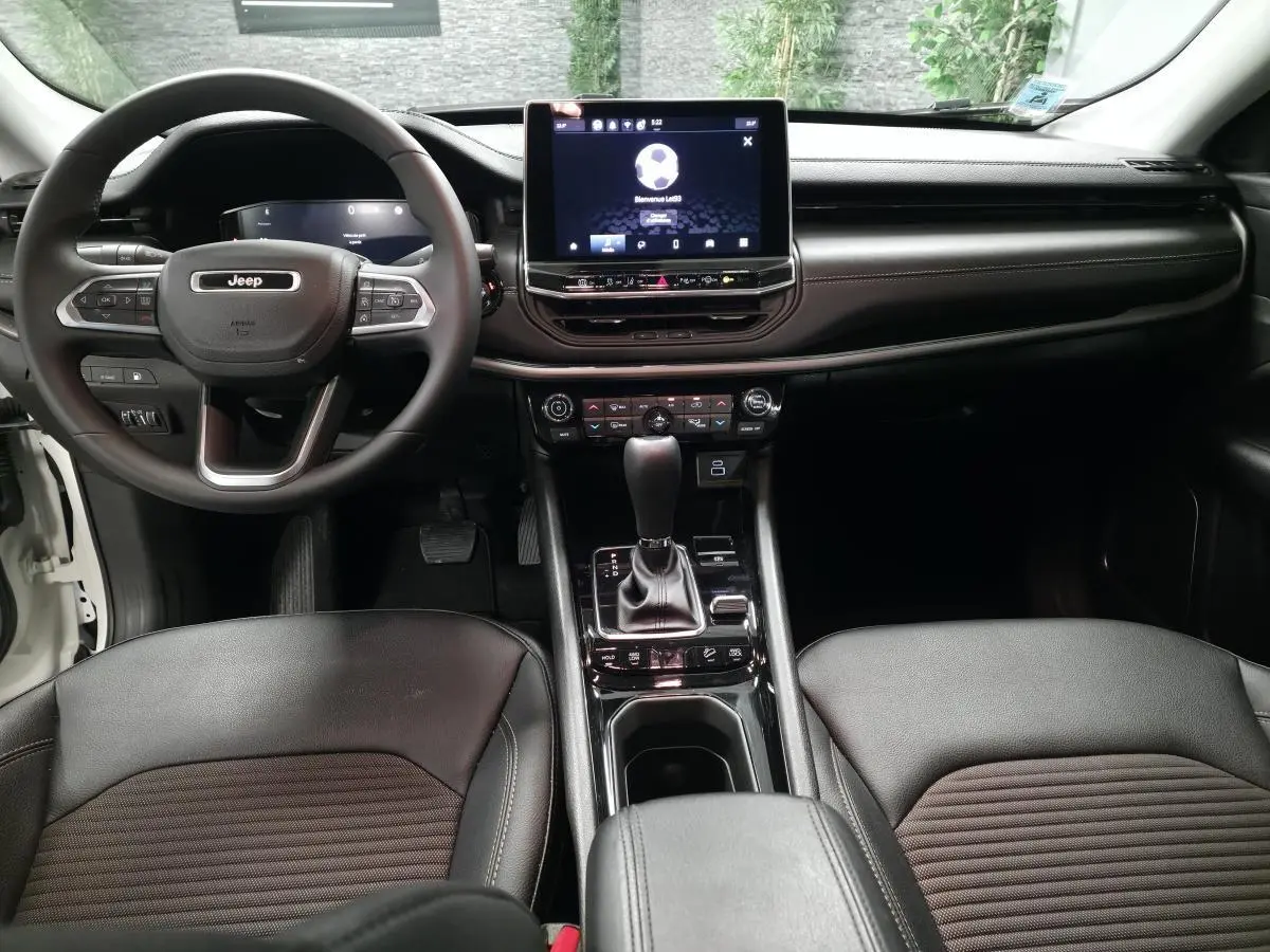 Vue intérieure frontale du tableau de bord et console centrale du Jeep Compass blanc avec sellerie noire mixte tissu et TEP.