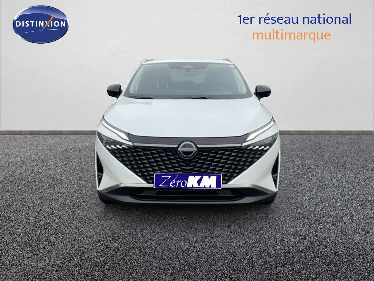 Vue de face du Nissan Qashqai blanc nacré métal 2025 avec calandre noire et phares LED fins.