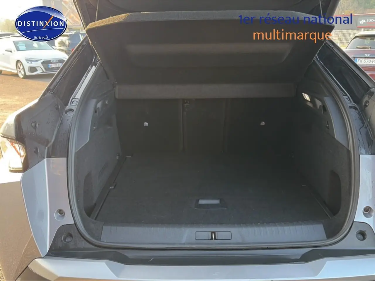 Coffre ouvert vue arrière d’un Peugeot 3008 gris 2025, montrant l’espace de chargement vide et les finitions intérieures.