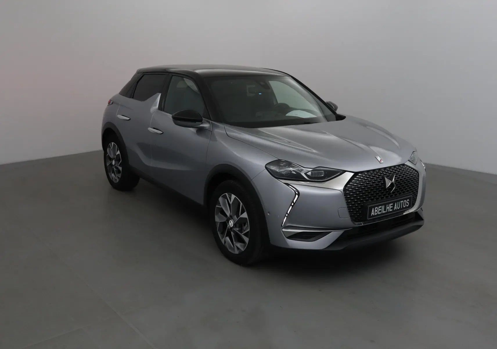 DS3 Crossback E-TENSE gris Artense vu en 3/4 avant droit, avec toit noir et calandre distinctive DS.