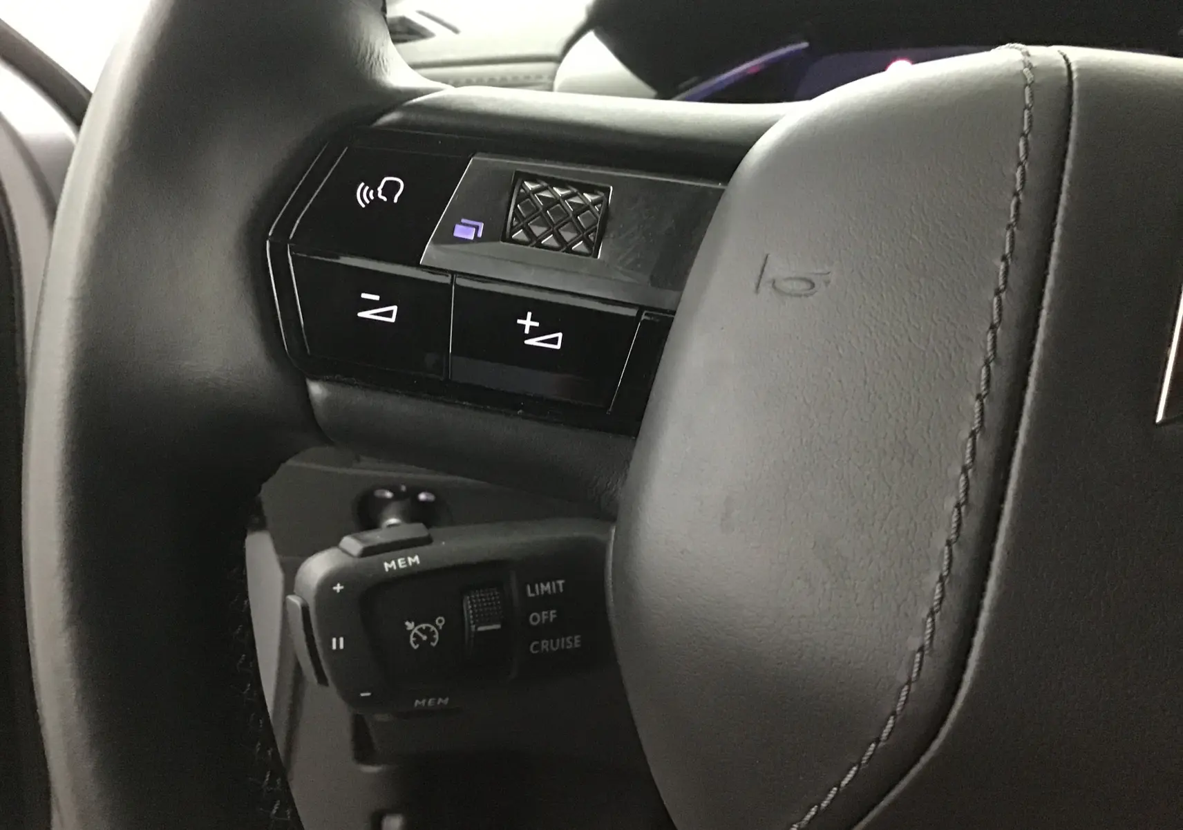 Gros plan sur la partie gauche du volant en cuir gris du DS3 Crossback E-TENSE avec commandes audio et régulateur de vitesse.