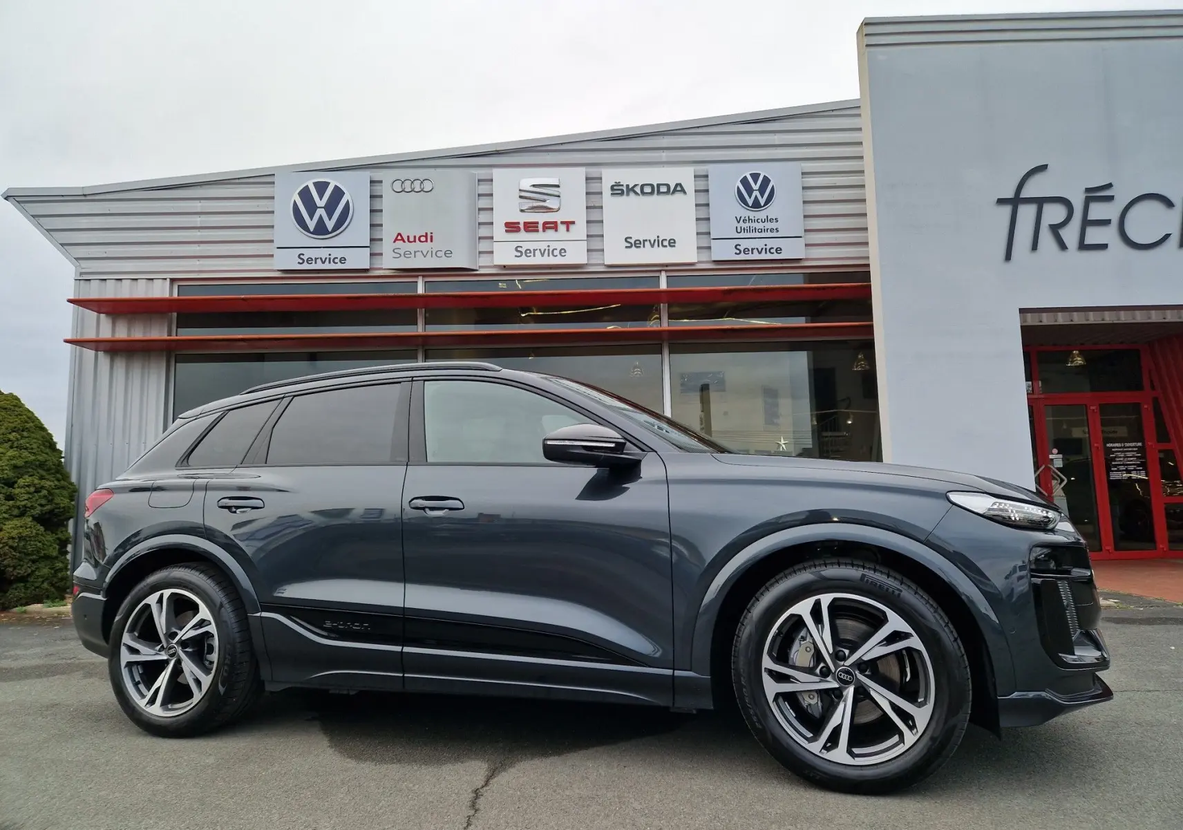 Audi Q6 e-tron Performance S-Line gris Manhattan vu de profil côté gauche, avec jantes Audi Sport et détails noirs.