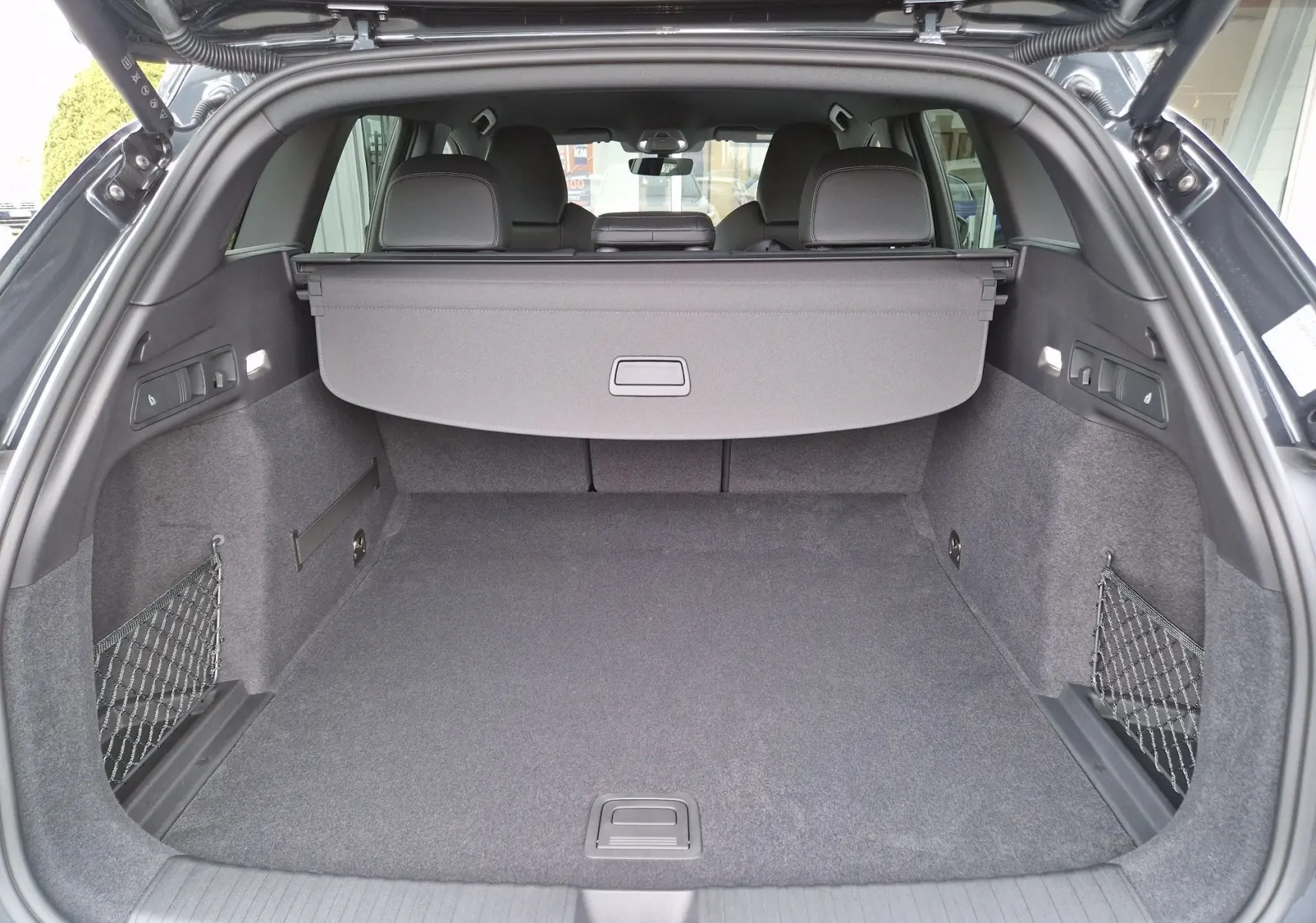 Coffre spacieux de l'Audi Q6 e-tron Performance S-Line gris Manhattan, vue arrière avec cache-bagages déployé.