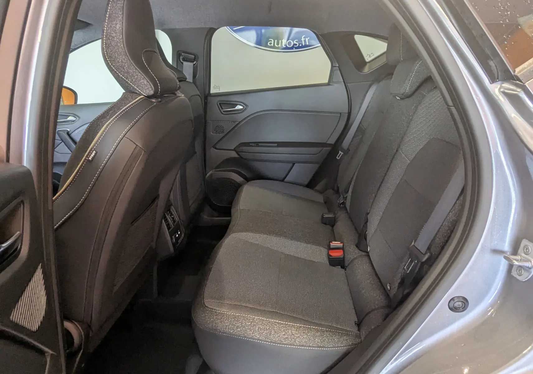 Vue côté droit de l'habitacle arrière du Renault Captur E-Tech gris Cassiopée, sièges tissu gris et ceintures visibles.