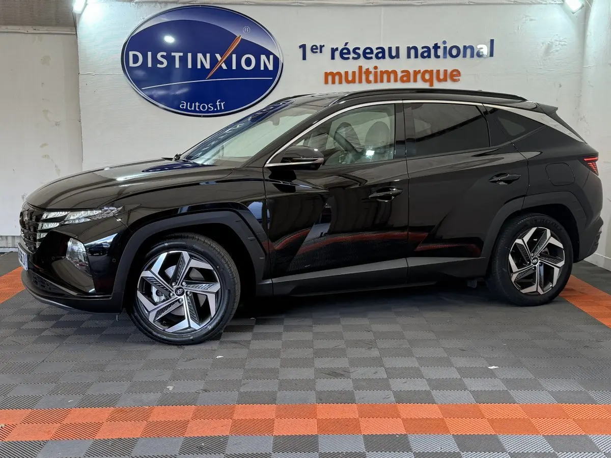 Profil droit d'un Hyundai Tucson noir 2022 avec jantes alliage modernes, stationné en intérieur showroom.