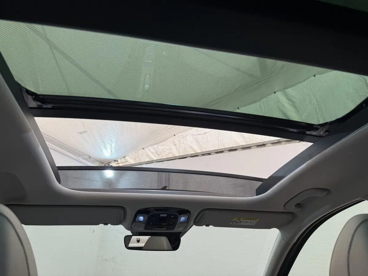 Toit ouvrant panoramique ouvert vu de l'intérieur avant du Hyundai Tucson noir 2022 avec ciel visible.