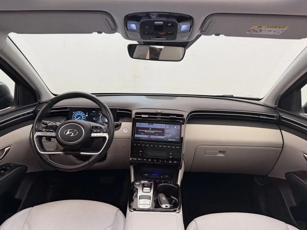 Intérieur avant du Hyundai Tucson 2022, tableau de bord beige et noir avec écran tactile central et volant multifonction.