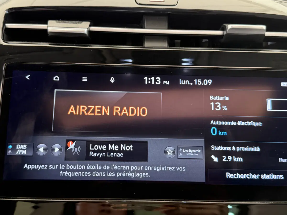 Gros plan sur l'écran tactile central du Hyundai Tucson noir, affichant la radio Airzen et l'état batterie à 13%