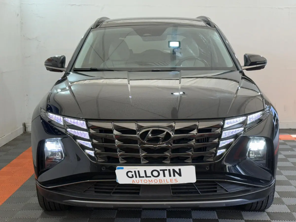 Vue frontale d'un Hyundai Tucson noir 2022 avec phares LED et calandre distinctive illuminée.