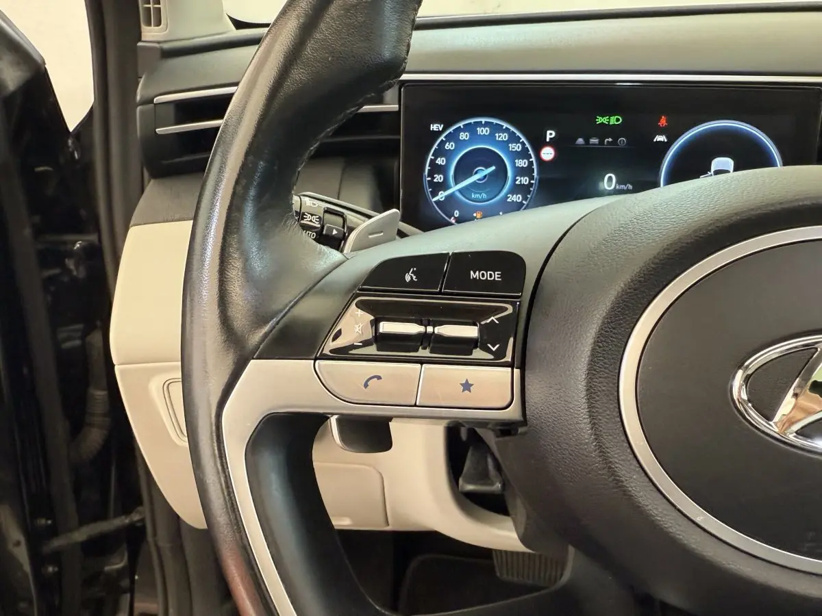 Gros plan sur le volant cuir noir et le tableau de bord digital du Hyundai Tucson 2022 hybride rechargeable.