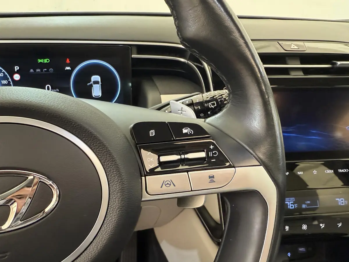 Gros plan sur le volant cuir noir du Hyundai Tucson 2022 avec commandes multifonctions et tableau de bord digital.