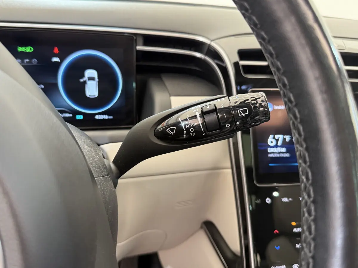 Gros plan sur la commande d'essuie-glace noire et le tableau de bord numérique du Hyundai Tucson noir 2022.