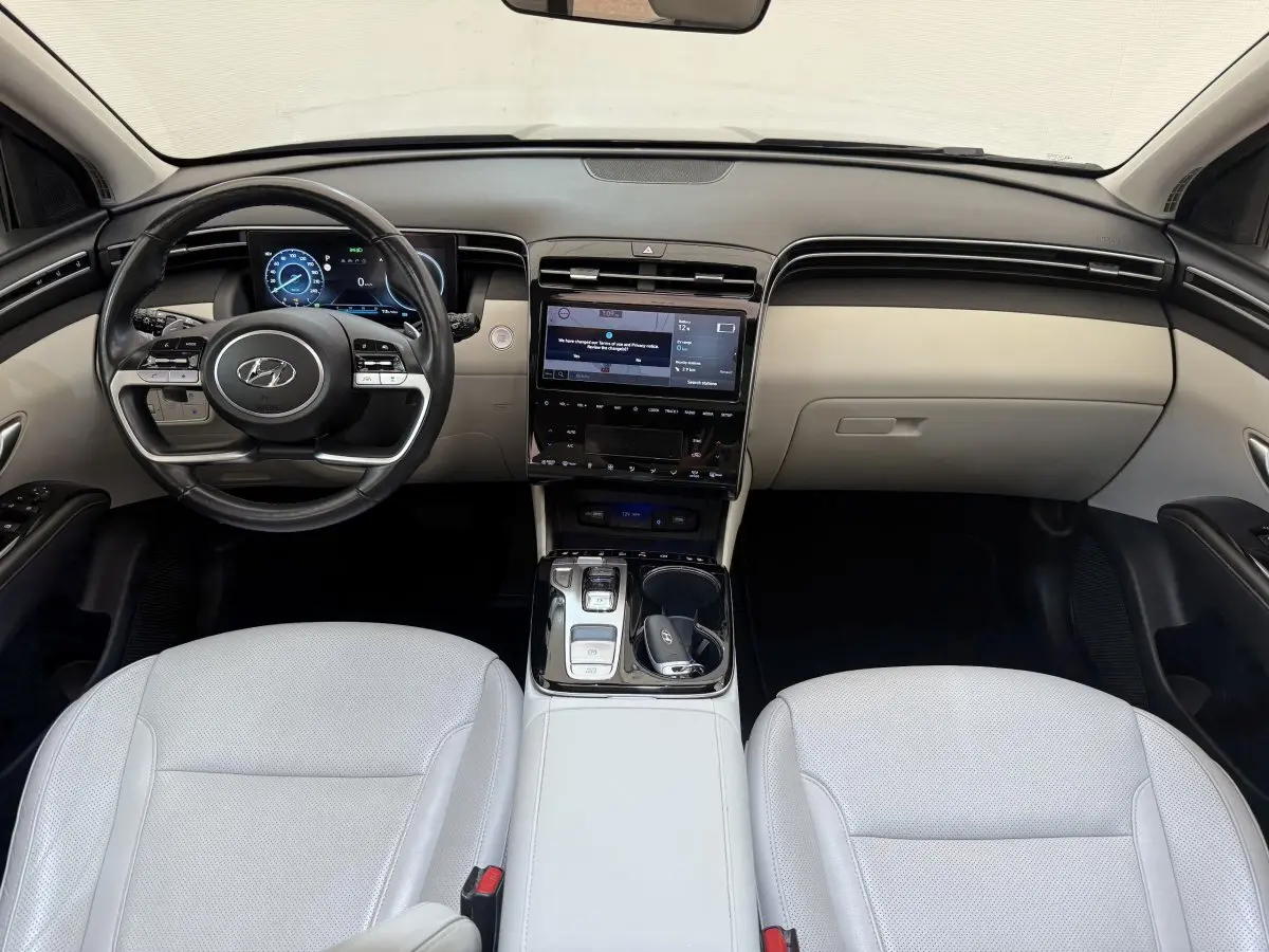 Intérieur clair du Hyundai Tucson 2022, vue frontale du tableau de bord avec écran tactile et volant multifonctions.