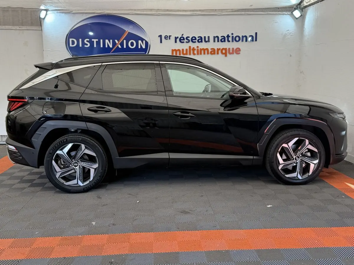 Profil côté gauche du Hyundai Tucson noir 2022 hybride rechargeable, avec jantes modernes et lignes anguleuses marquées.