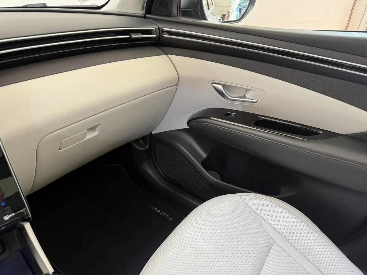 Vue intérieure côté passager avant du Hyundai Tucson 2022 noir, avec sellerie claire et tableau de bord épuré.