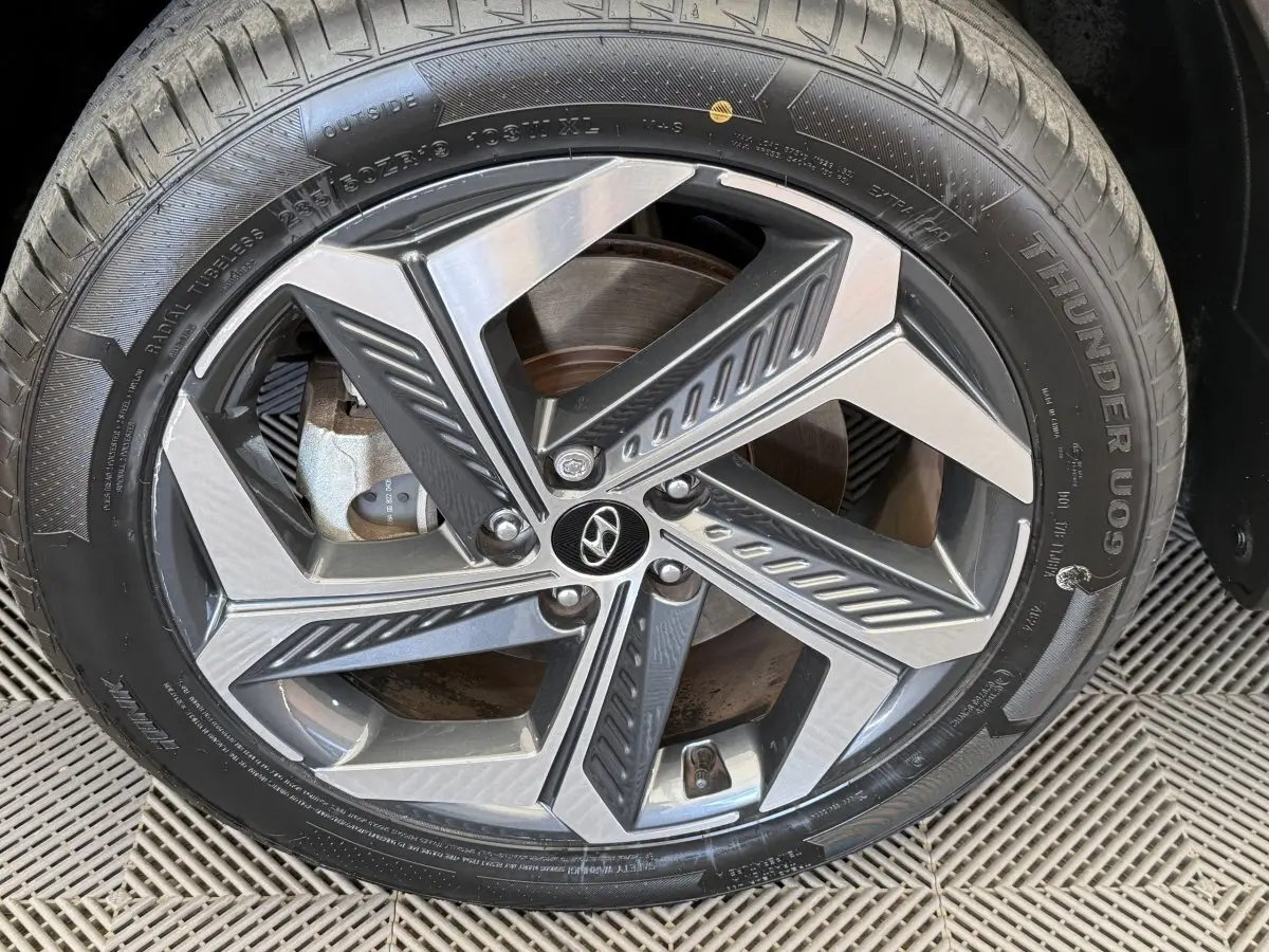 Gros plan sur la jante alliage au design géométrique du Hyundai Tucson noir 2022, avec logo Hyundai central.