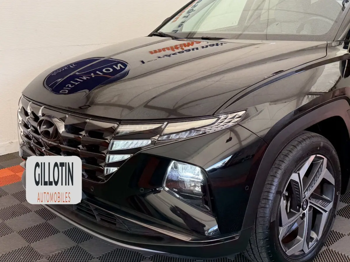 Vue 3/4 avant droit du Hyundai Tucson noir brillant avec calandre distinctive et jante alliage moderne.
